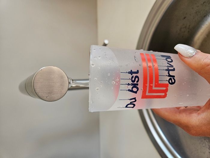 Bild von einem Glas unter einem laufenden Wasserhahn